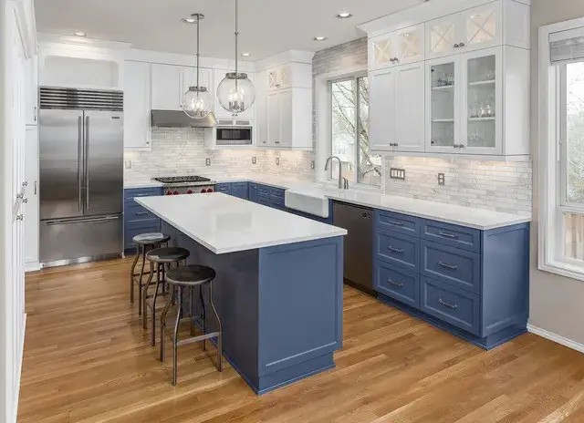 A modern kitchen featuring blue lower cabinets and a quartz island by a home remodeler in Woodside, DE.