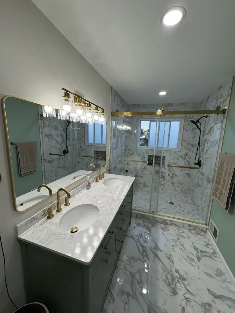 Modern bathroom renovation featuring marble tile and brass fixtures by a home remodeler in Felton, DE.